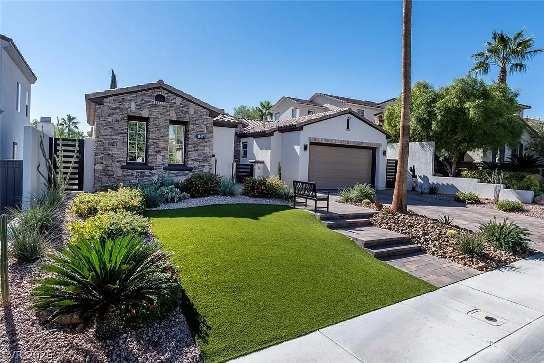 Front elevation of 11477 Timber Mountain Avenue, a single-story stone-facade residence inside Red Rock Country Club, with desert landscaping and mature palms